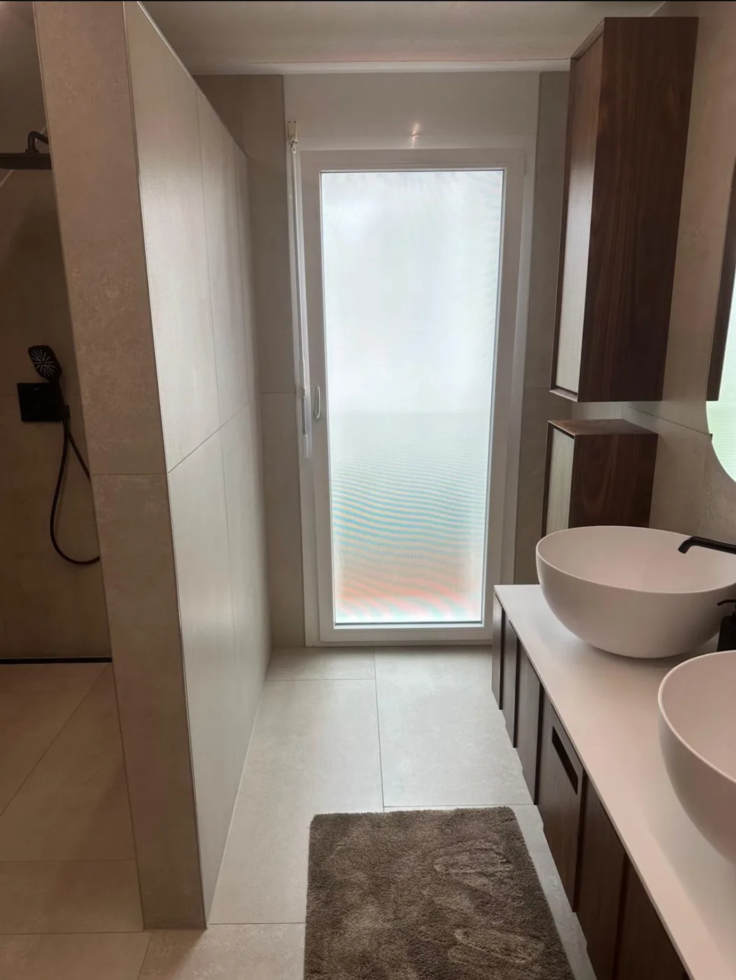 Badezimmer in Schöftland mit Dusche, Waschtisch und Plattenbelägen